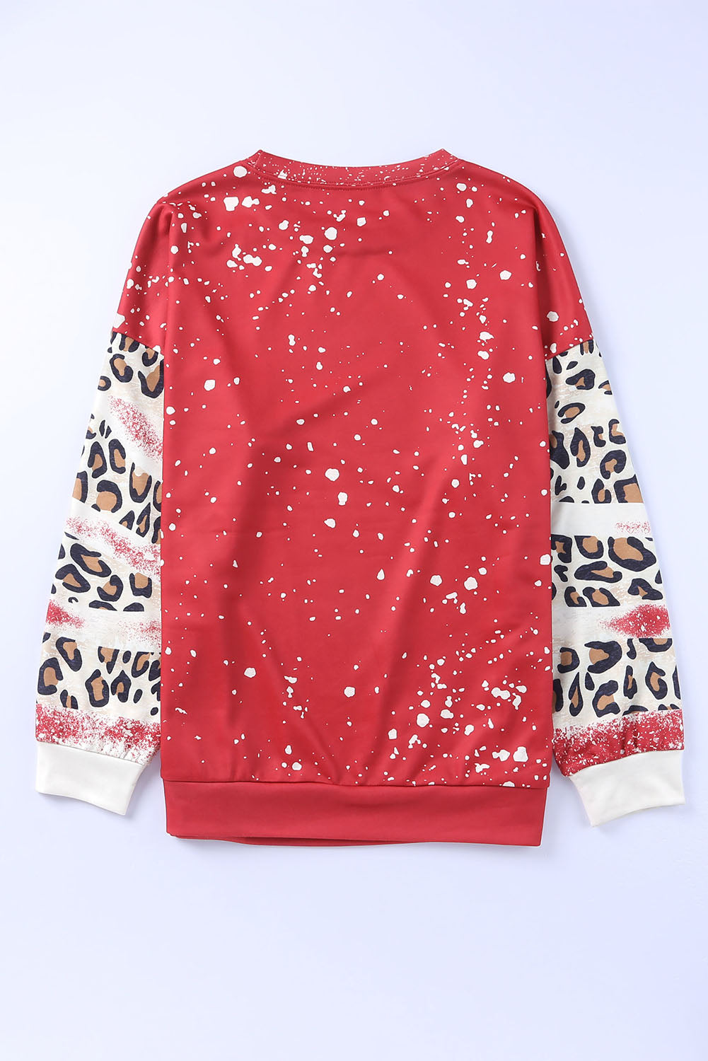 A person with wavy hair is seen from the back wearing the Fiery Red Tie Dye Leopard Drop Shoulder Sweatshirt, creating a stylish look with its red hue adorned with paint splatters and leopard print sleeves. They are also wearing jeans, showcasing a casual sweatshirt that's perfect for any laid-back occasion.