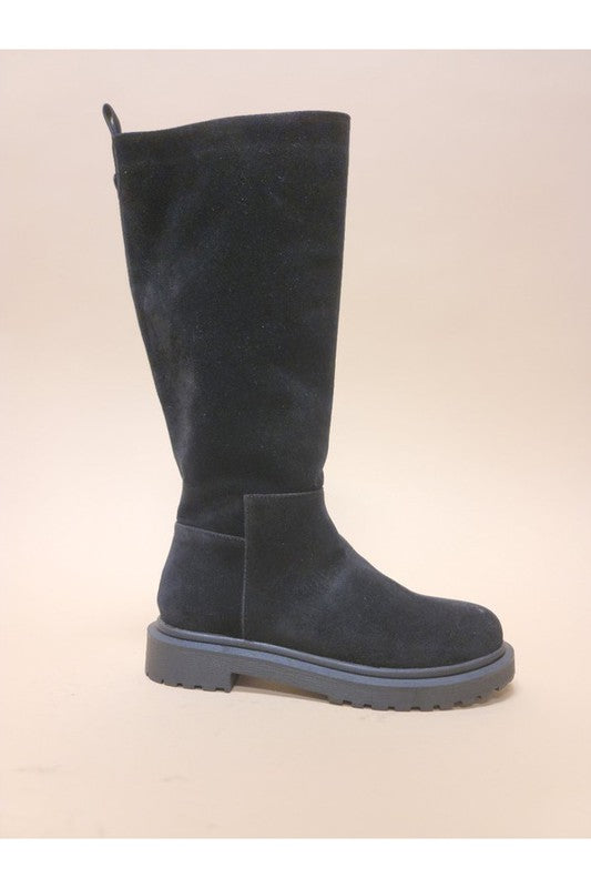 Three pairs of UNA-LONG BOOTS in beige, grey, and black are aligned in a row against a neutral background. These casual suede long boots feature chunky rubber soles and block heels.