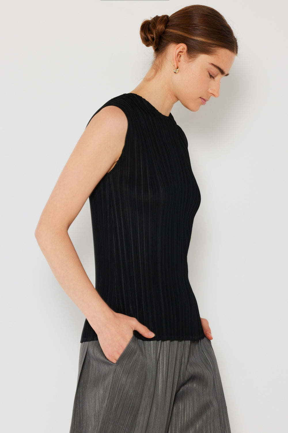 Person wearing a Marina West Swim Pleated Sleeveless Crewneck Tank and a gray pleated skirt, standing against a white background.