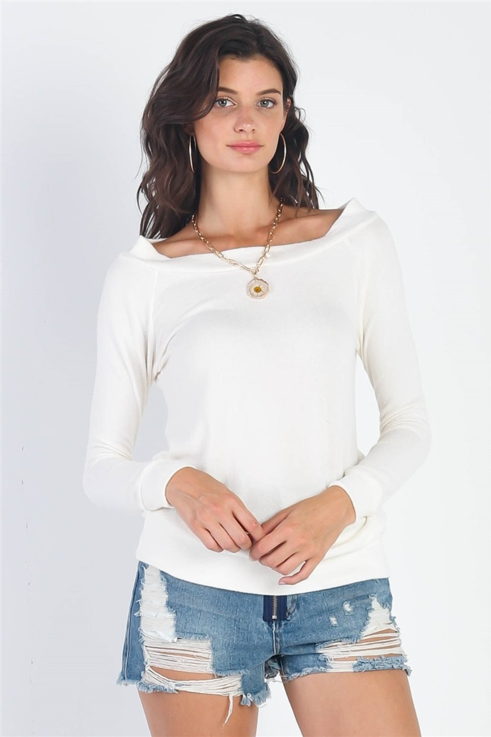 A woman stands against a plain background, wearing the cozy and versatile Cherish Apparel Flannel Long Sleeve Top and distressed denim shorts. She has long, wavy hair, hoop earrings, and a pendant necklace.