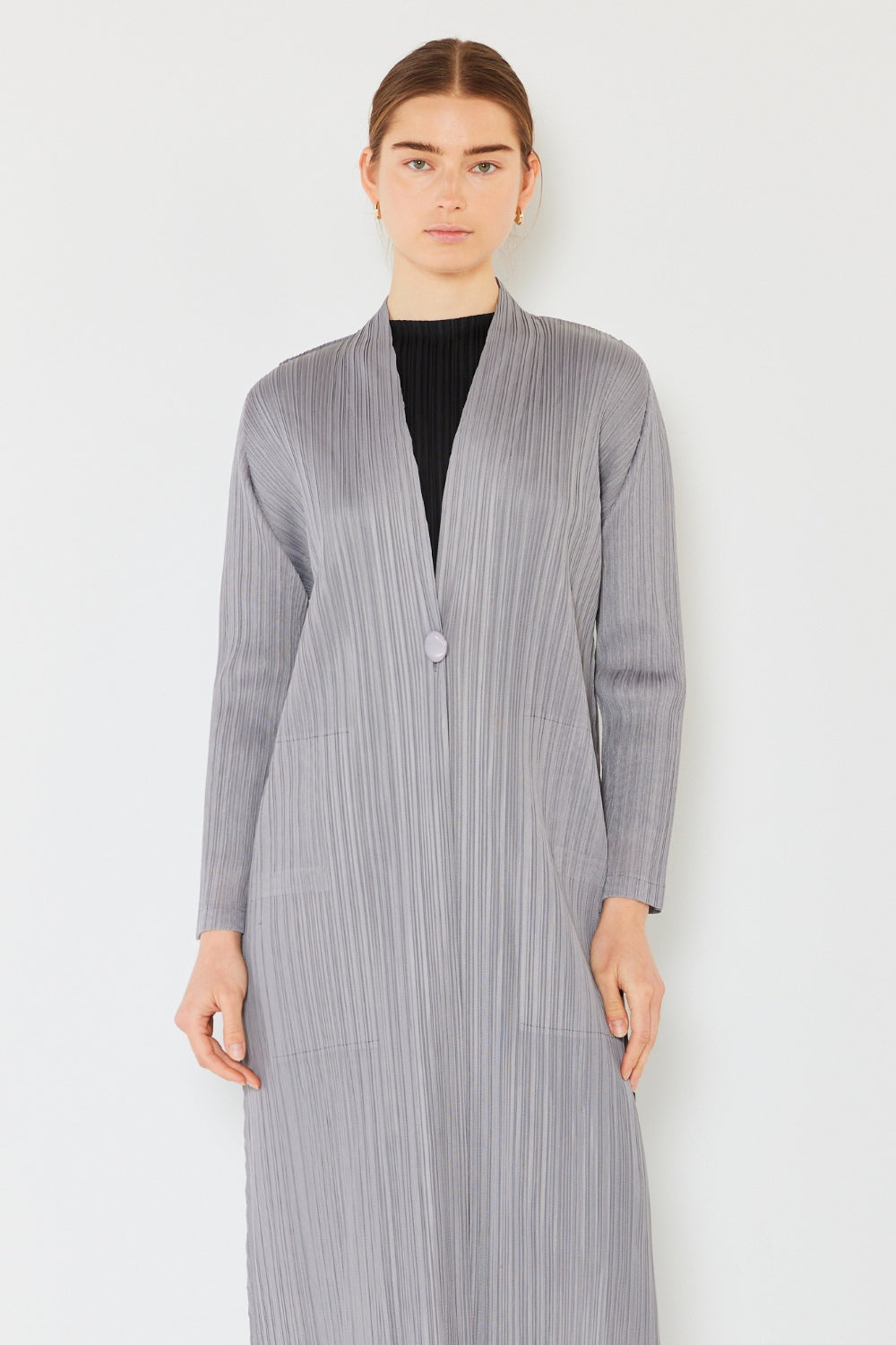 A person wears the Marina West Swim Pleated Long Sleeve Cardigan over a matching top and gray wide-leg pants, standing against a plain light background. This versatile layering piece, with its chic pleated long sleeves, adds an elegant touch to the ensemble.