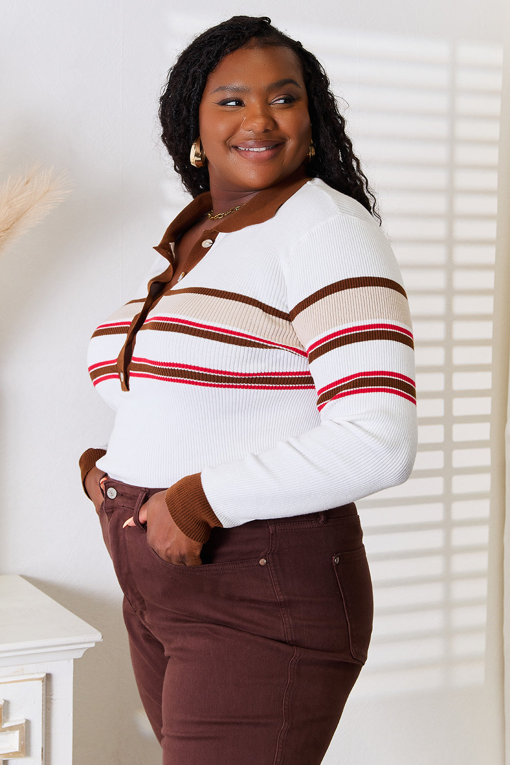 A person wearing the Basic Bae Striped Collared Neck Rib-Knit Top and dark pants is smiling and standing indoors against a light background.