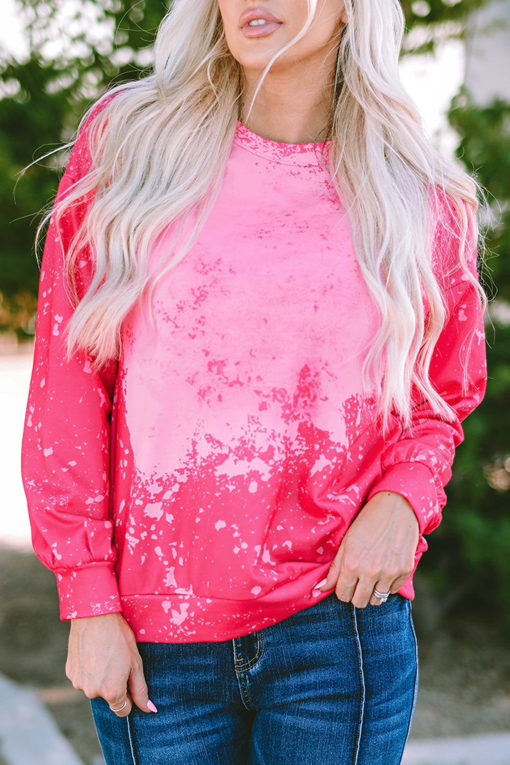 Person with long blonde hair wearing a Rose Tie Dye Long Sleeve Pullover Sweatshirt and blue jeans, standing outdoors with back to the camera.