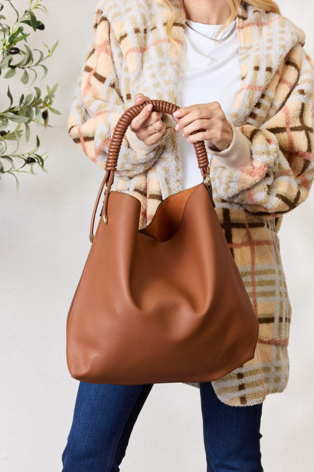 Person carrying a SHOMICO Vegan Leather Handbag with a front pocket and coiled handles, showcasing both versatility and durability.