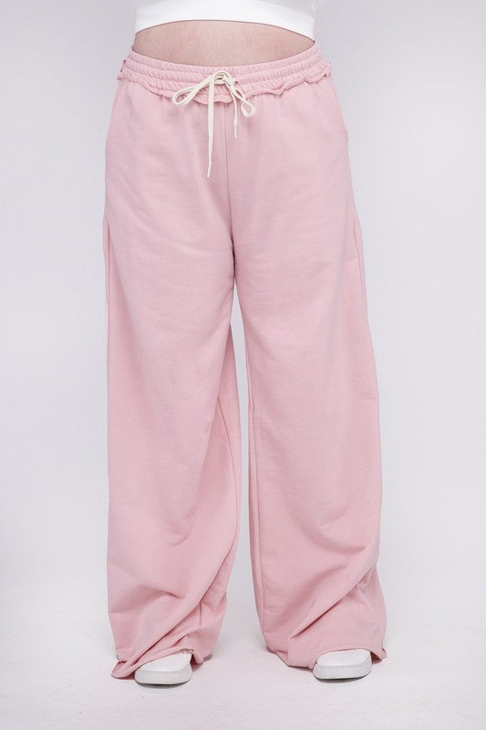 A person wearing the Plus F/Terry Drawstring Waist Raw Edge Hem Pants in pink, paired with white shoes, stands against a plain background.