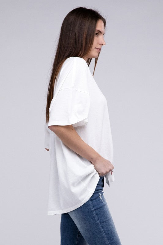 A person with long hair wearing an Oversized T-Shirt in beige with short sleeves and blue jeans, standing against a neutral background.