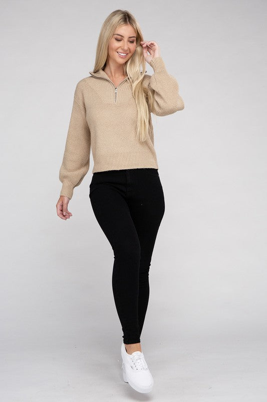 A person with long blonde hair wears a stylish cozy top—an Easy-Wear Half-Zip Pullover in grey—and blue jeans while looking down.