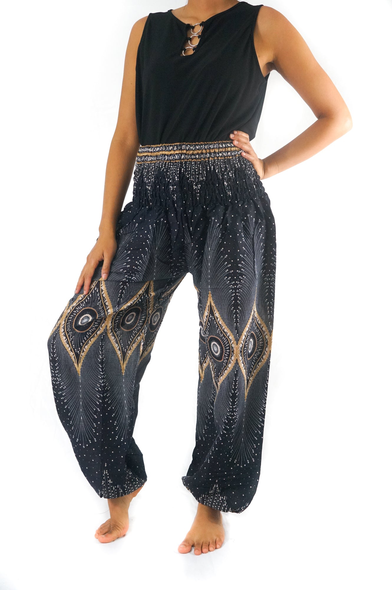 Person wearing a sleeveless black top and Black PEACOCK Women Boho Pants Hippie Pants Yoga Pants with an elastic waist, standing barefoot against a white background. The harem pants are made from 100% Rayon, ensuring both comfort and style.