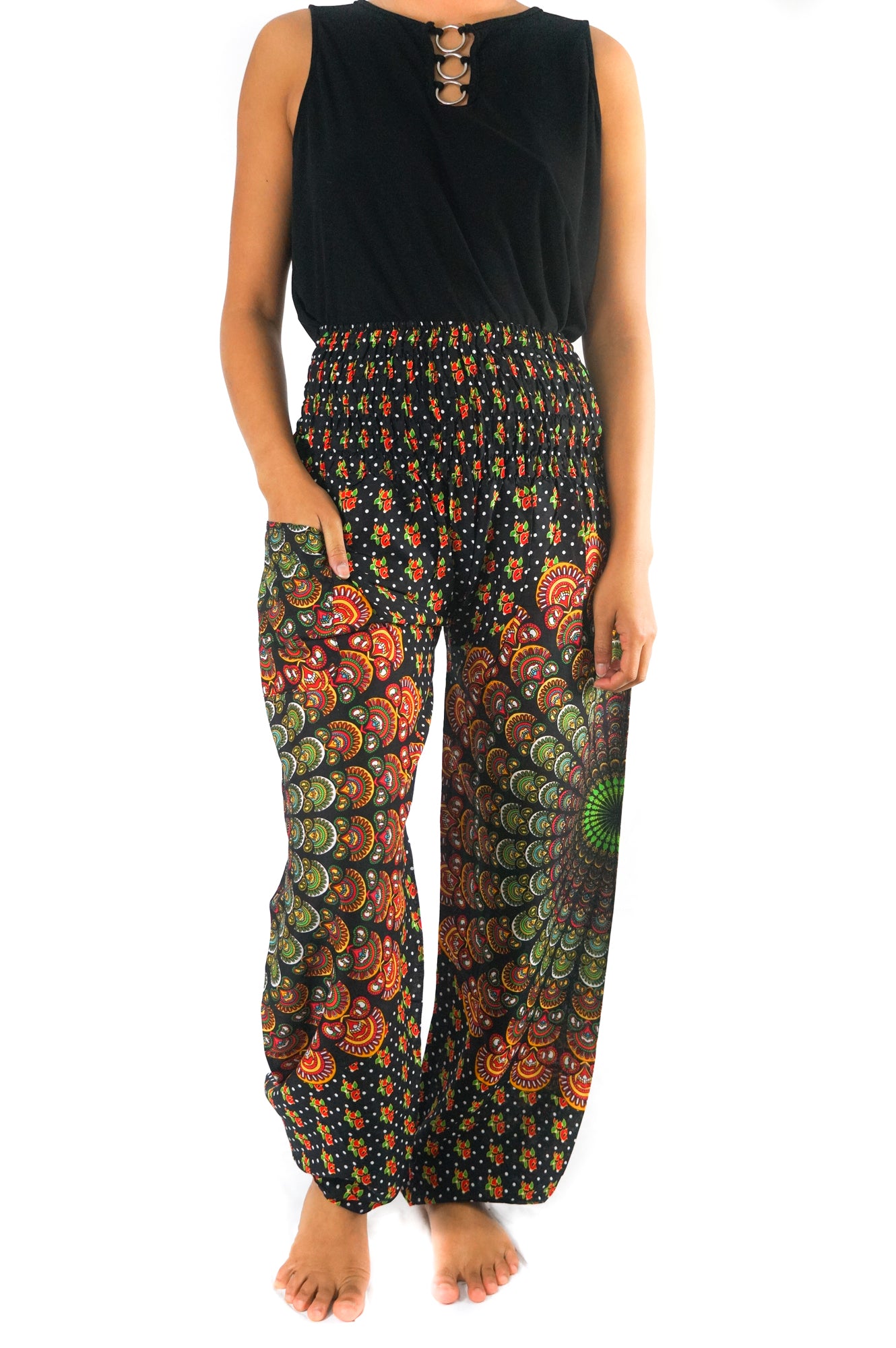 A person stands barefoot, wearing a unisex sleeveless black top and the brightly patterned, colorful high-waisted "Black Chakra Harem Pants, Hippie Pants, Boho Pants" made from 100% Rayon.