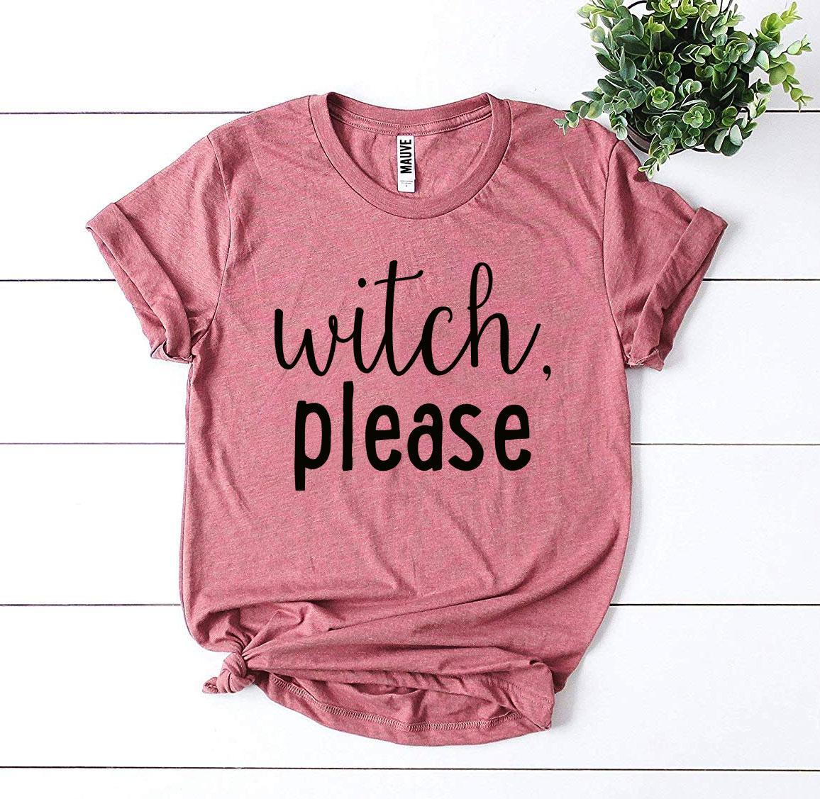 A Witch Please T-shirt in gray, celebrated for its soft texture and comfortable retail fit, is beautifully laid out next to a pair of blue jeans, beige high heels, and a bouquet of flowers.