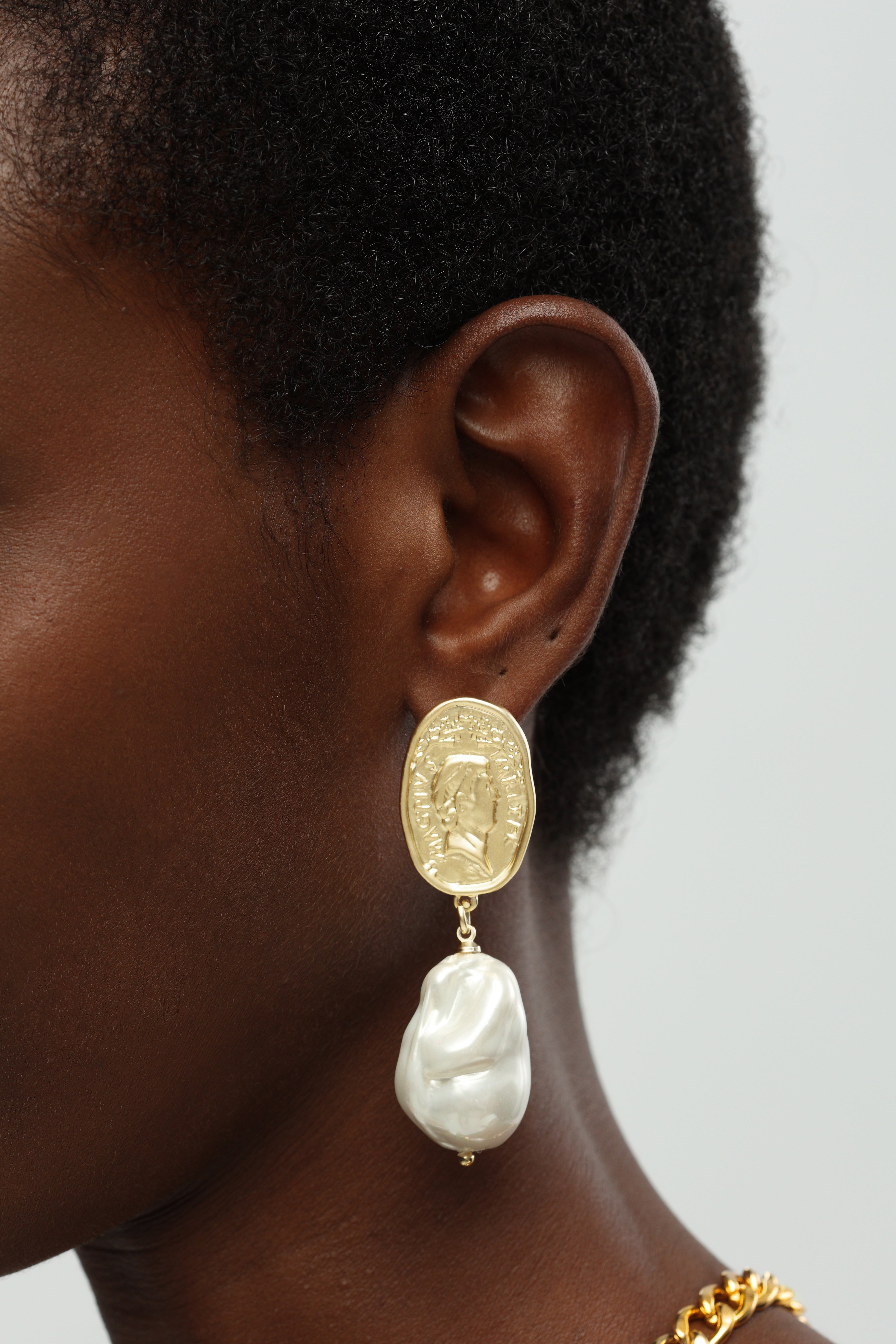 A pair of earrings featuring Matted Gold Sculpted Oversized Baroque Pearl Drop Earrings.
