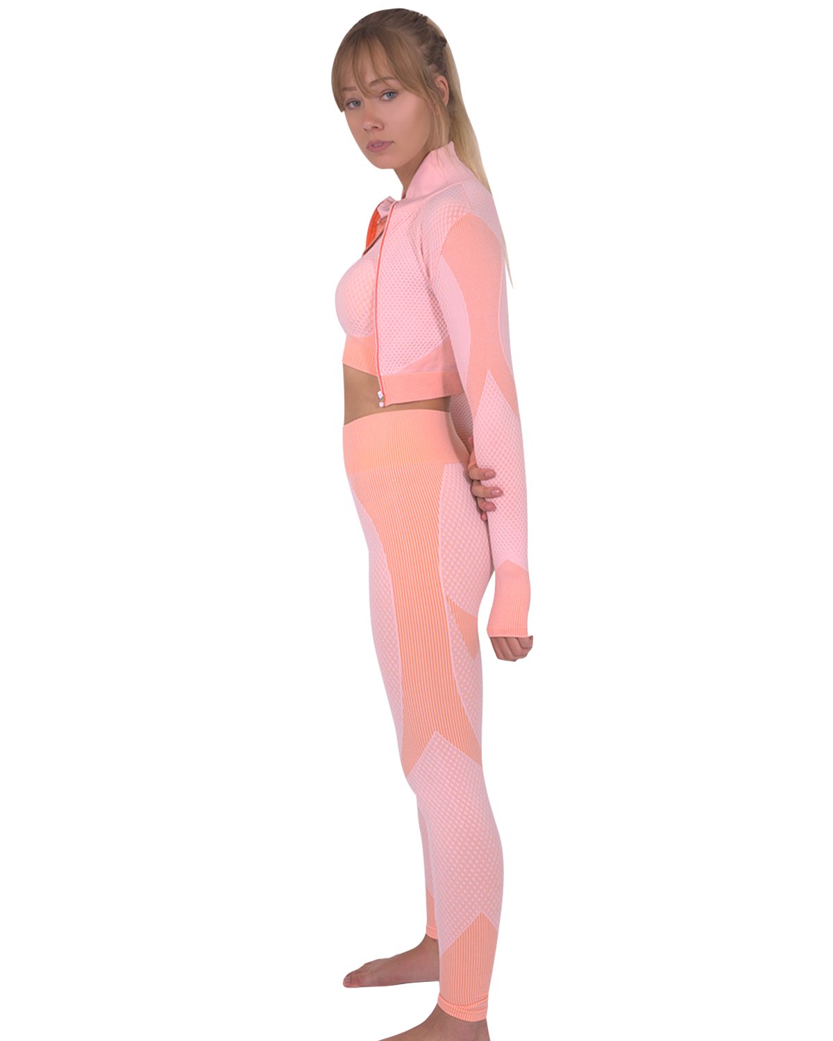 Here’s a person donning a coordinated pink and orange workout ensemble featuring the Trois Seamless Sports Jacket in Pink, along with a sports bra and leggings. They have their hair styled in a ponytail, highlighting their distinctive and chic look.