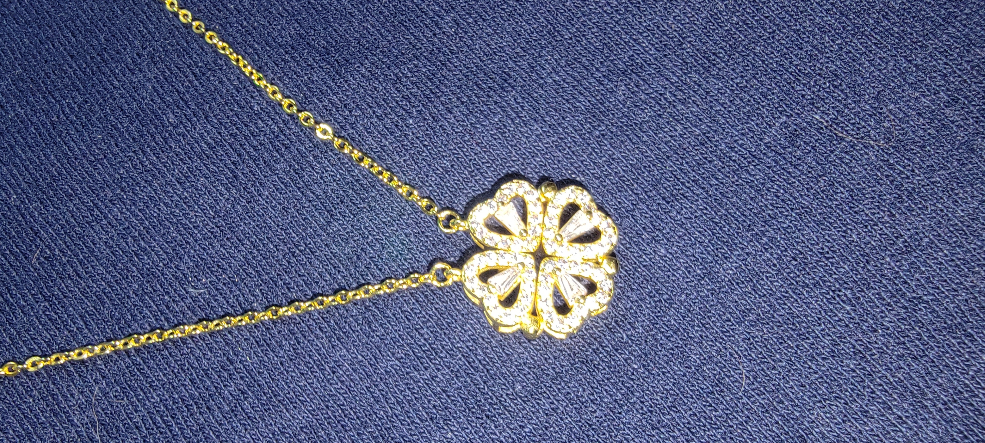 A person is holding a LuckyClover- Four Leaf Heart Shape Necklace.