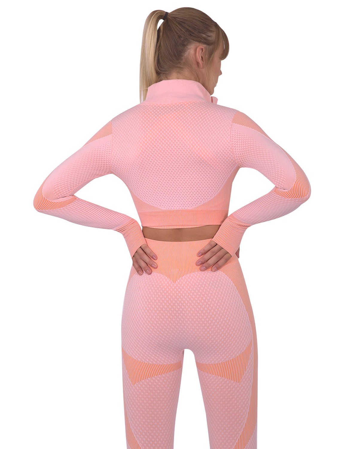 Here’s a person donning a coordinated pink and orange workout ensemble featuring the Trois Seamless Sports Jacket in Pink, along with a sports bra and leggings. They have their hair styled in a ponytail, highlighting their distinctive and chic look.