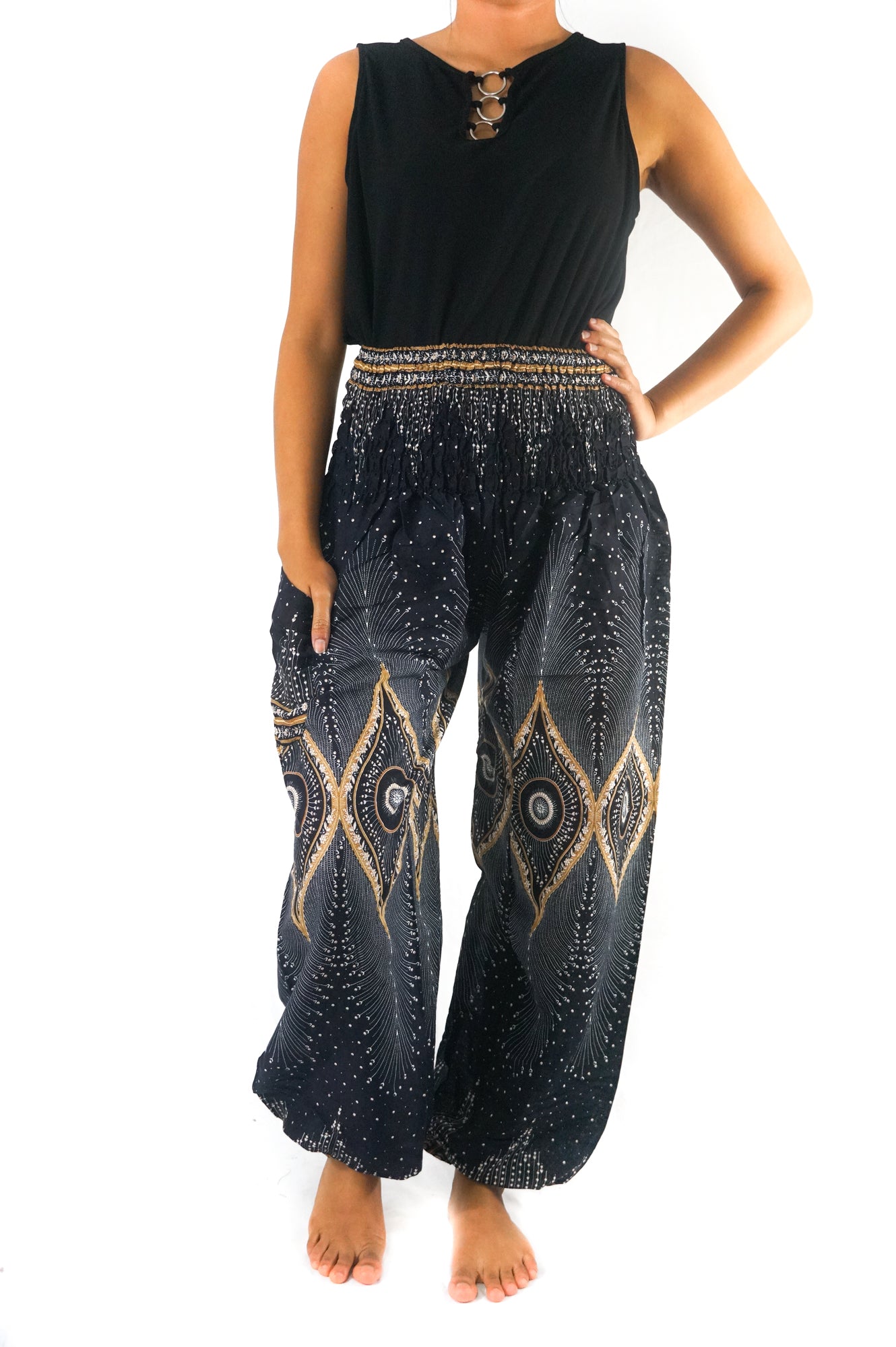 Person wearing a sleeveless black top and Black PEACOCK Women Boho Pants Hippie Pants Yoga Pants with an elastic waist, standing barefoot against a white background. The harem pants are made from 100% Rayon, ensuring both comfort and style.