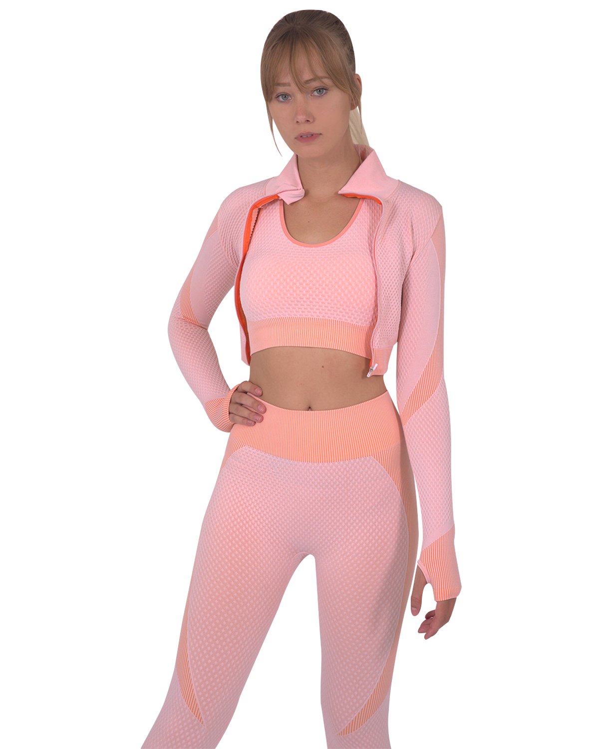 Here’s a person donning a coordinated pink and orange workout ensemble featuring the Trois Seamless Sports Jacket in Pink, along with a sports bra and leggings. They have their hair styled in a ponytail, highlighting their distinctive and chic look.