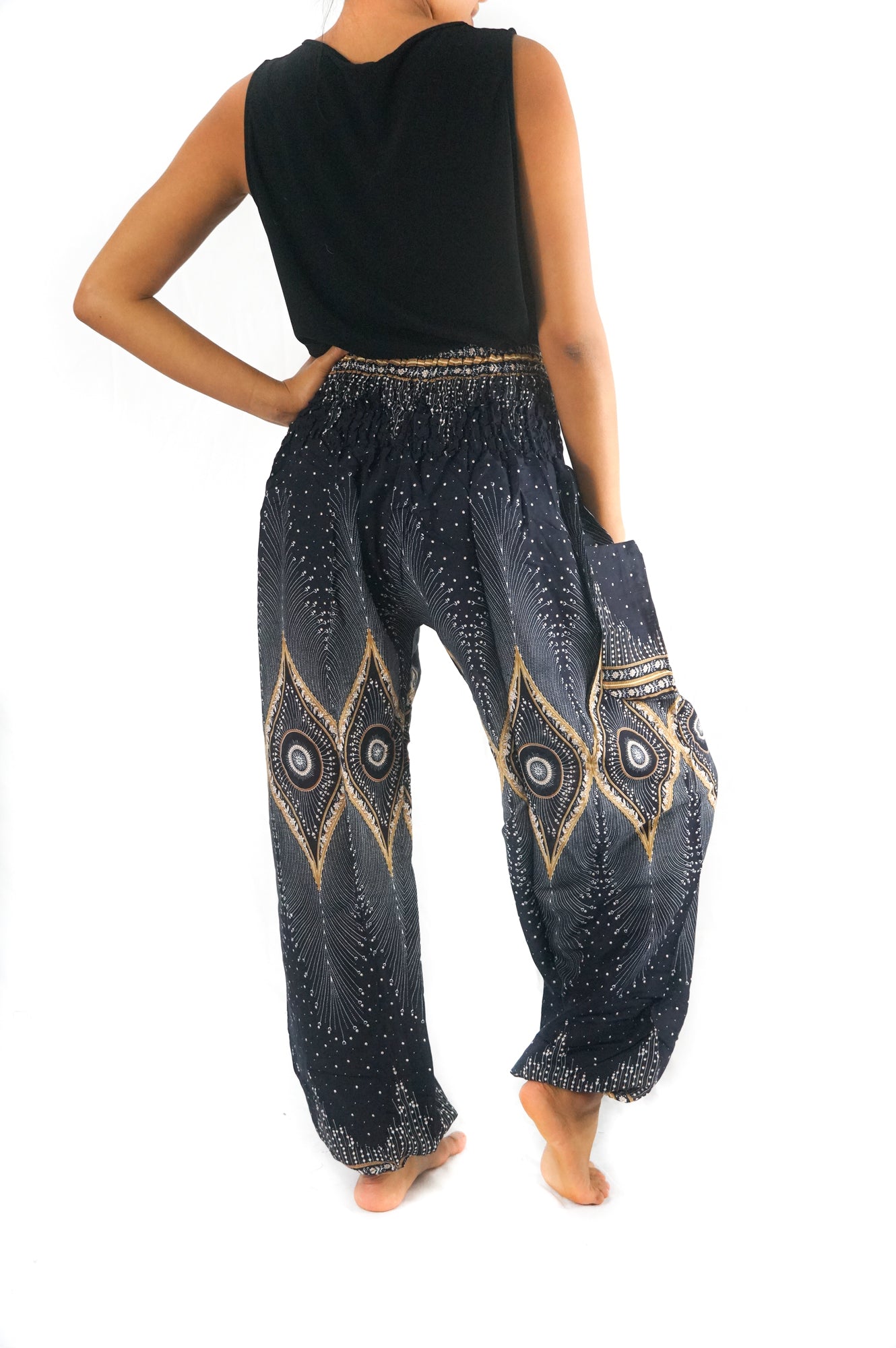 Person wearing a sleeveless black top and Black PEACOCK Women Boho Pants Hippie Pants Yoga Pants with an elastic waist, standing barefoot against a white background. The harem pants are made from 100% Rayon, ensuring both comfort and style.