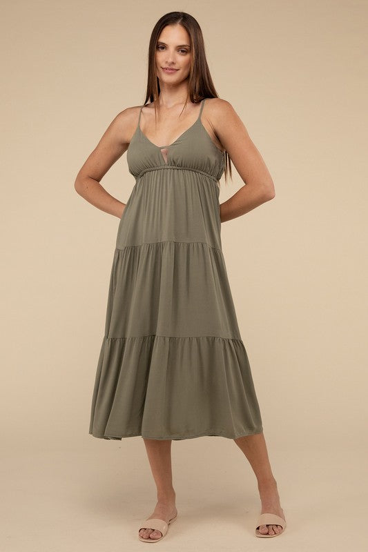 A woman wearing a teal woven sweetheart neckline tiered cami midi dress and sandals, standing against a neutral background.