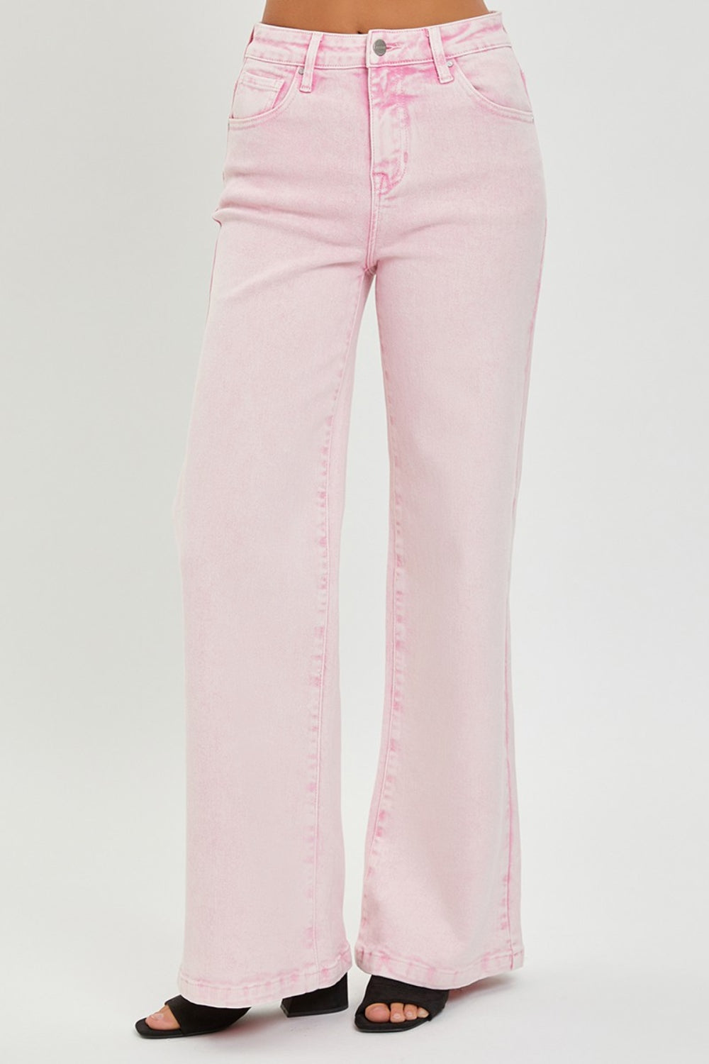 Someone is wearing RISEN Full Size High Rise Tummy Control Wide Leg Jeans in light pink, paired with black heeled sandals against a plain white background.