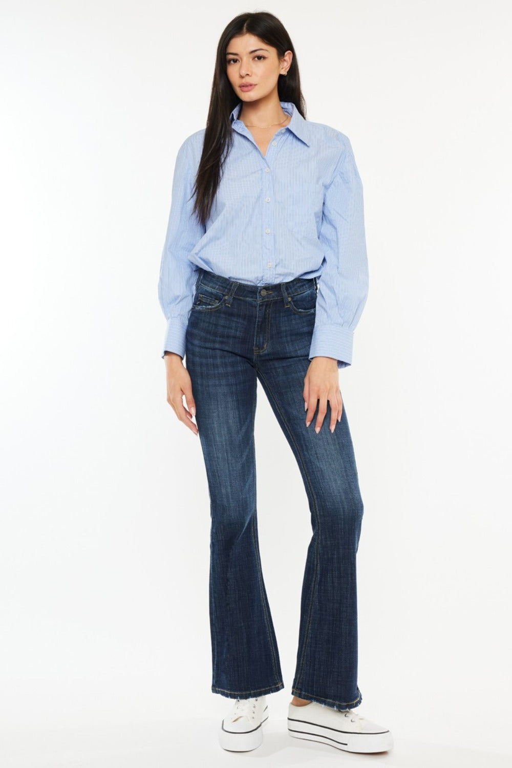 A person poses in a sleeveless brown top, Kancan Full Size Mid Rise Flare Jeans, and sneakers against a plain white background.