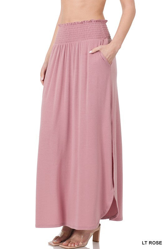 A person is elegantly dressed in a Smocked Waist Side Slit Maxi Skirt with Pockets in deep coral, beautifully paired with clear heeled sandals.