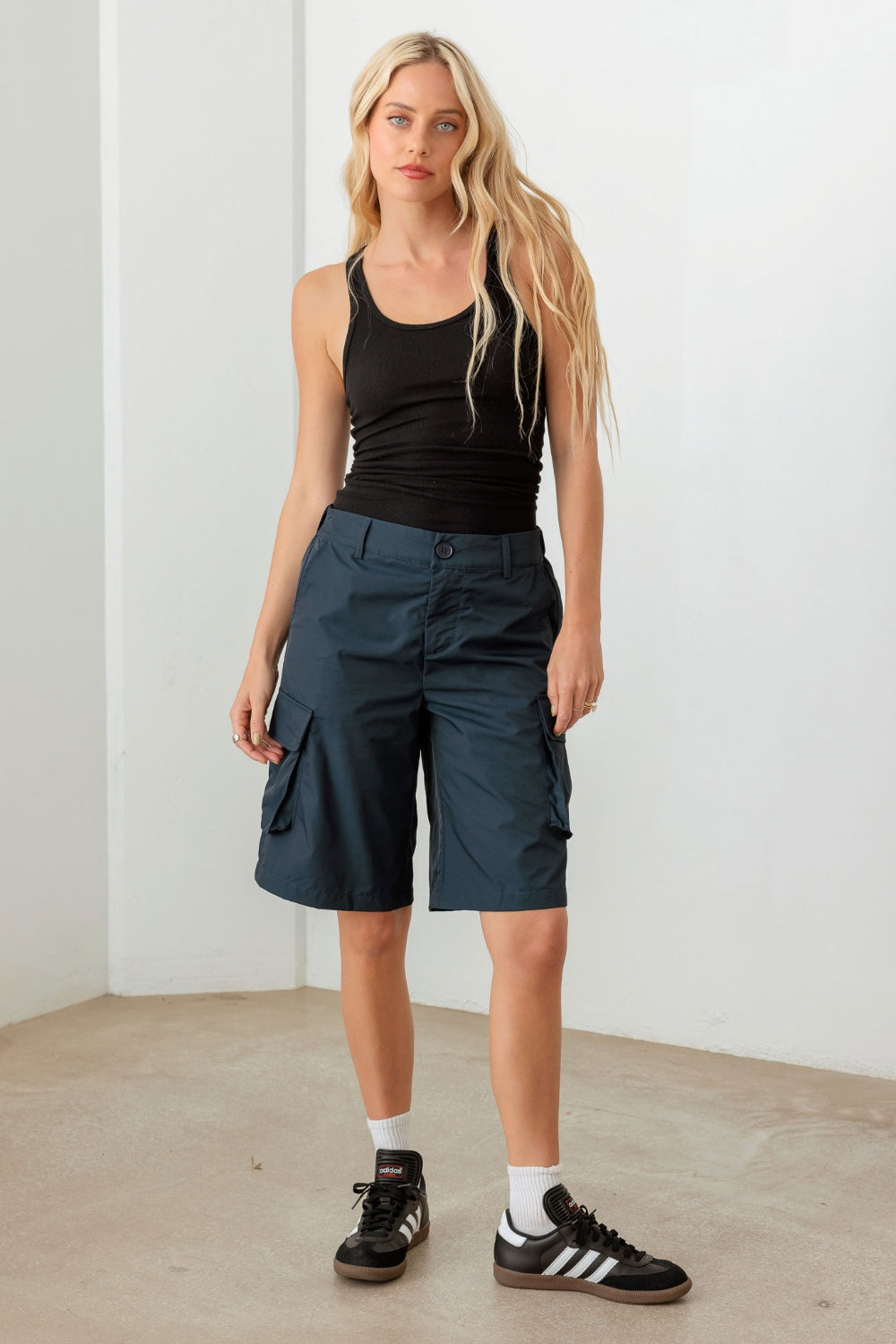 Person wearing a black sleeveless top and Le Lis Navy Cargo Bermuda Shorts with pockets, perfect for a warm-weather wardrobe.