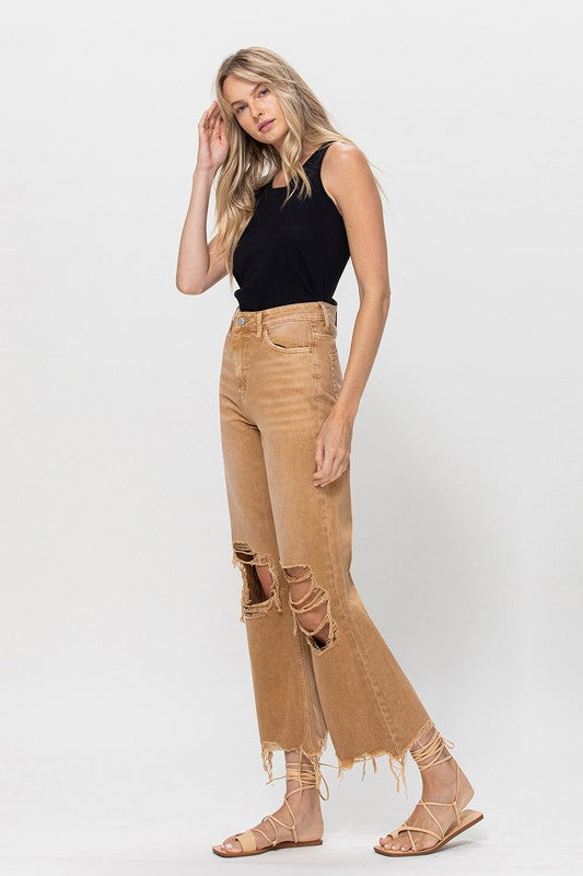 A person wearing 90's Vintage Crop Flare in a brown color and strappy sandals, standing against a plain background.