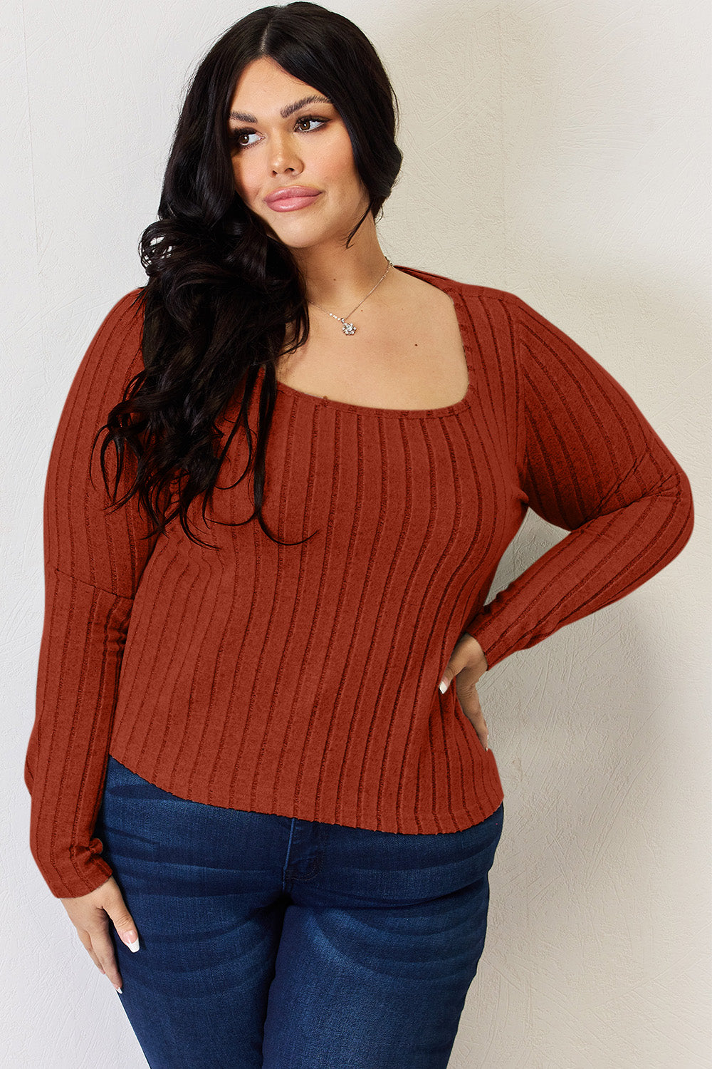 A person is standing and smiling, wearing the Basic Bae Full Size Ribbed Long Sleeve T-Shirt in light brown along with jeans. The basic style is perfect for any casual outing.