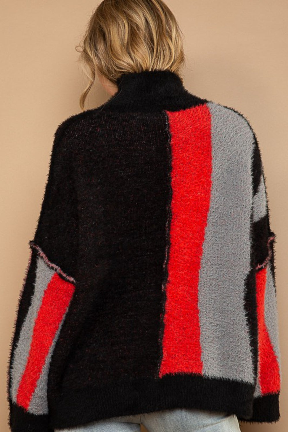 A person with long hair smiles while wearing the chic POL Turtleneck Color Block Fringe Detail Sweater in black, red, and gray.