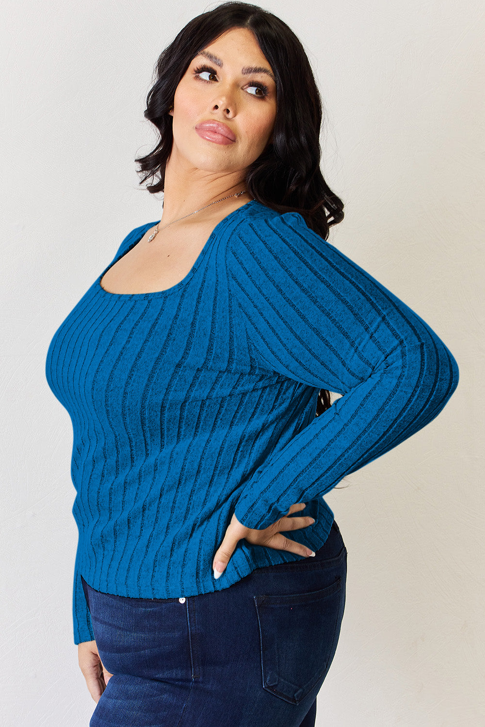 A person is standing and smiling, wearing the Basic Bae Full Size Ribbed Long Sleeve T-Shirt in light brown along with jeans. The basic style is perfect for any casual outing.