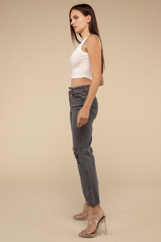 Person wearing acid washed high waist distressed straight pants and beige sandals against a neutral background.