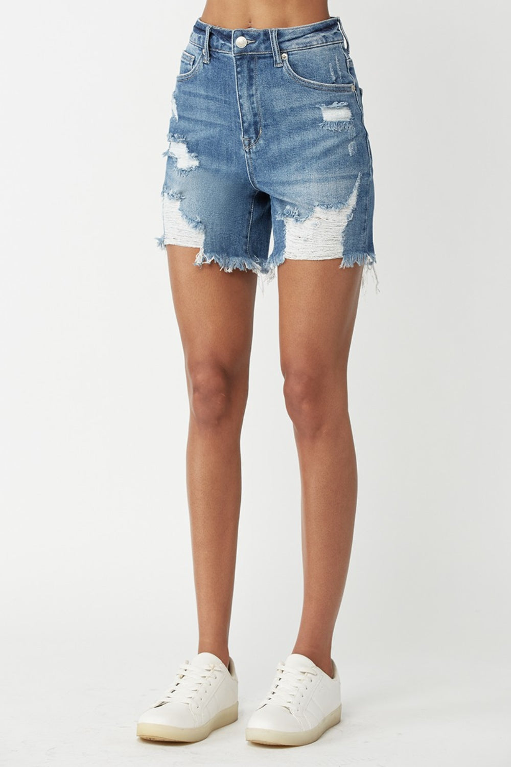 A person wearing RISEN High Waisted Distressed Denim Shorts with frayed detailing and a faded wash. This summer essential embodies an edgy style perfect for warm days.