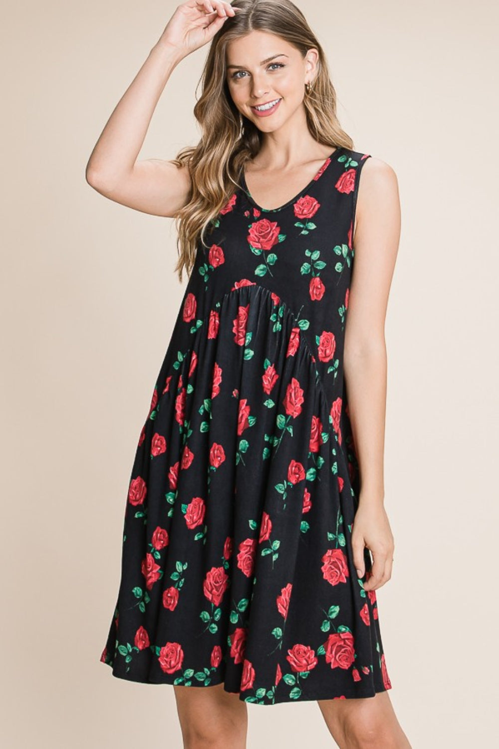 A woman is wearing a sleeveless BOMBOM Floral Ruched Tank Dress adorned with a black and red rose pattern. She is smiling and standing against a neutral background.