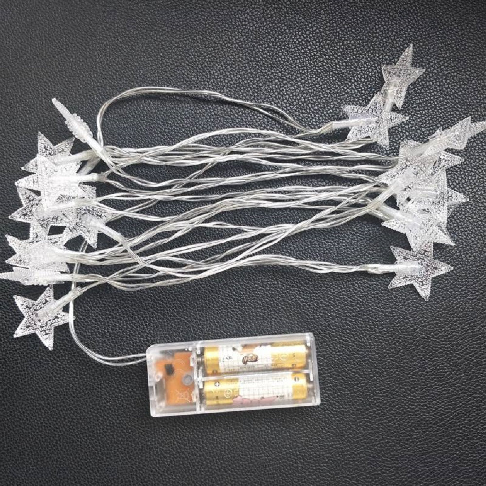 A purple children's Outdoor Indoor Portable Folding Princess Castle Tent Kids Children Funny Play Fairy House Kids Play Tent(LED Star Lights) illuminated by fairy lights at night, set up outdoors near a building.