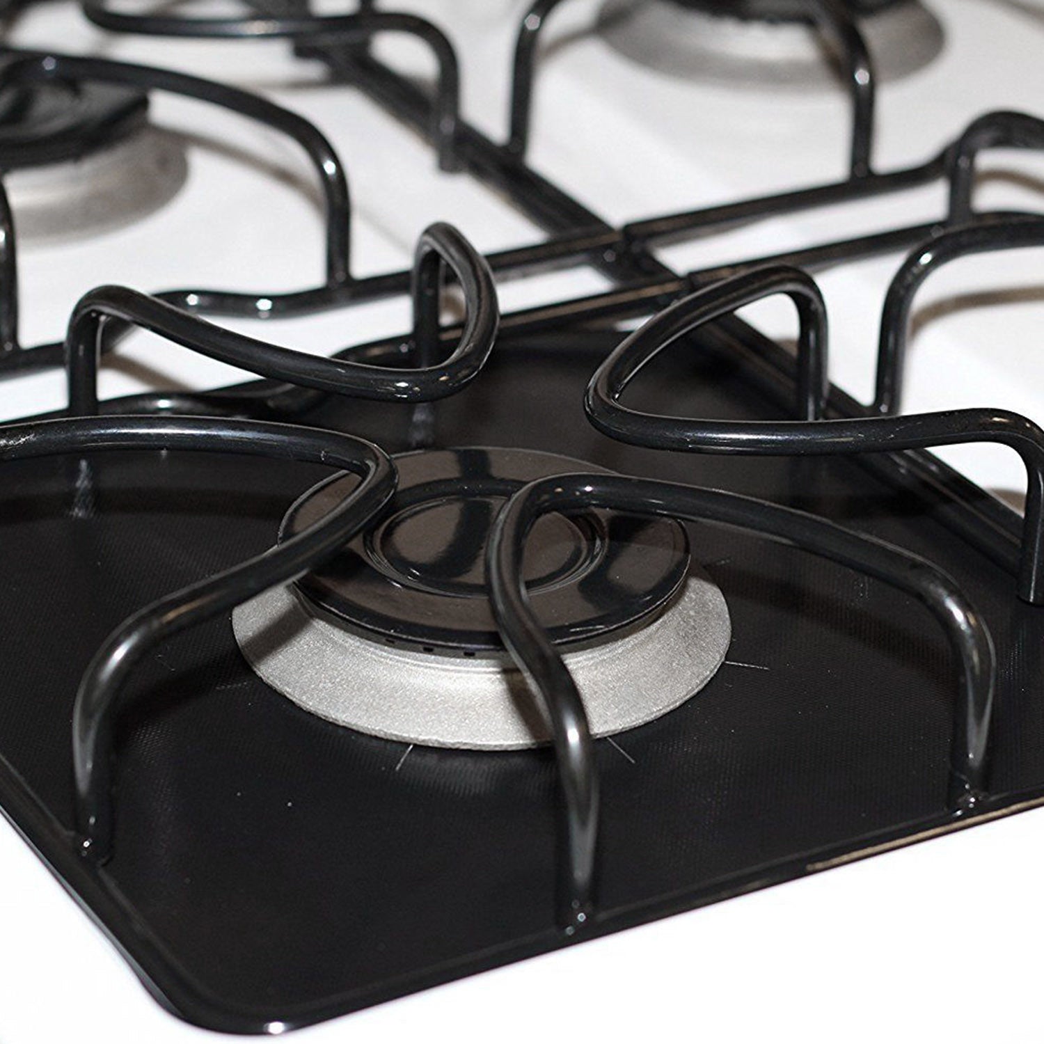 A stack of 4-Pack Reusable Nonstick Stovetop Burner Protector Liner papers with a white circle and crossing lines symbol in the center of the top sheet, treated with a PTFE coating.