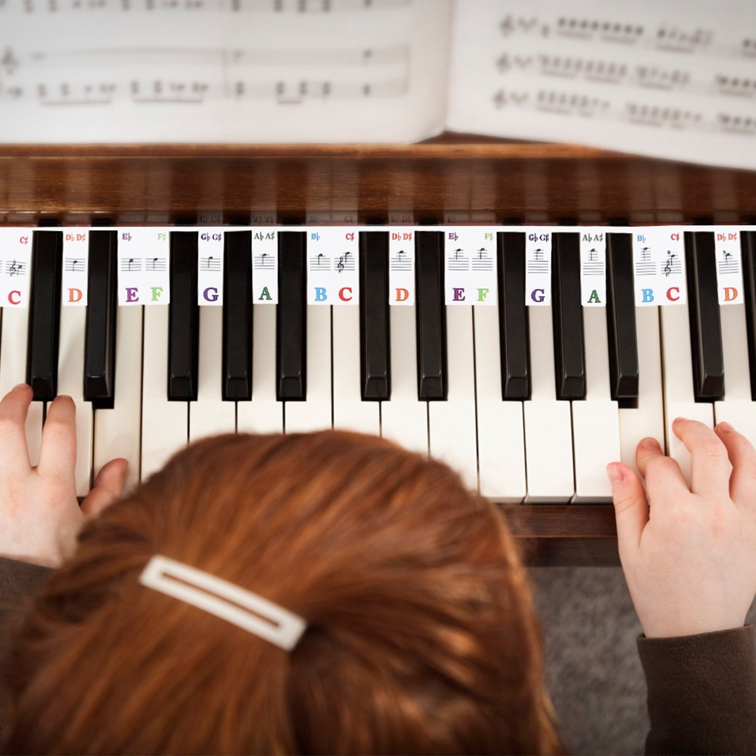 Piano Keyboard Stickers Removable Piano Key Labels PVC Piano Notes Guide without Glue for Beginners Kids with musical notes and corresponding letters, displayed in a loop beside a small round container with a metallic lid.
