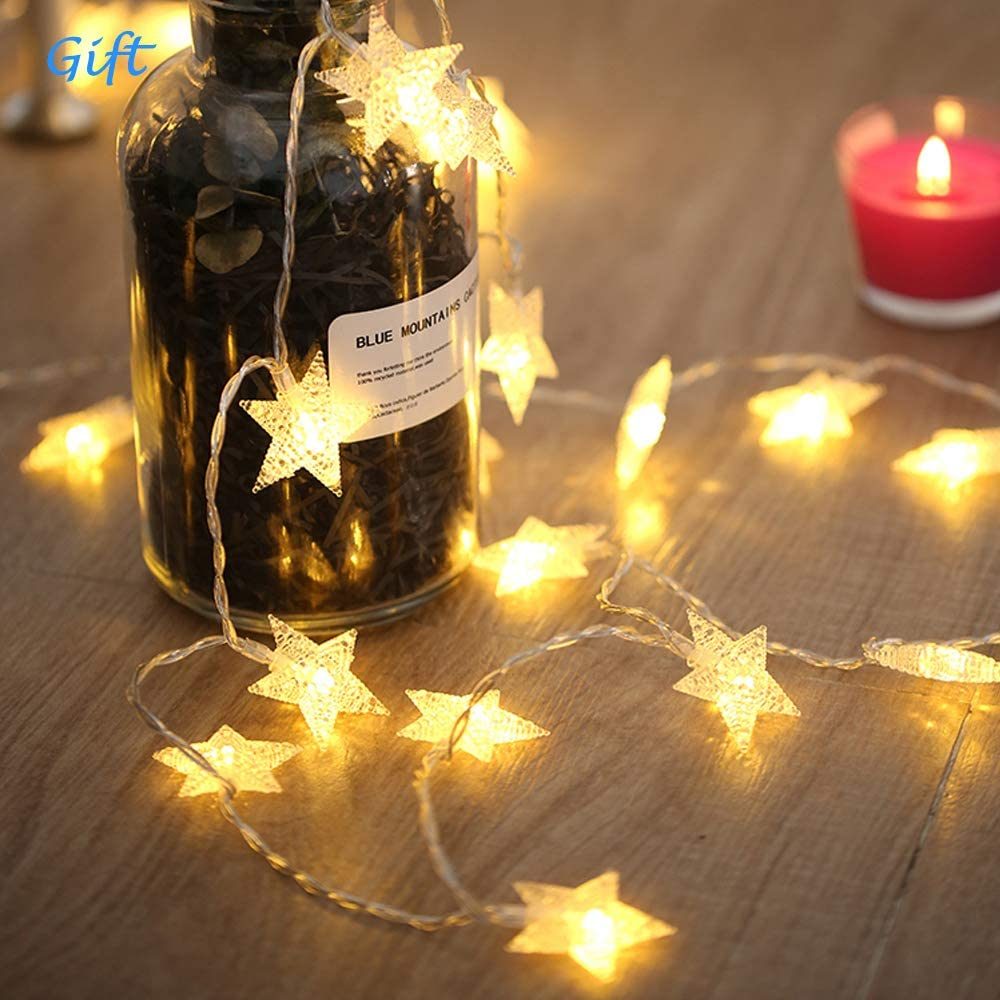 A pink Outdoor Indoor Portable Folding Princess Castle Tent Kids Children Funny Play Fairy House Kids Play Tent with its flap open, displaying several teddy bears inside, illuminated by string lights, with a star-shaped light visible at the top corner.