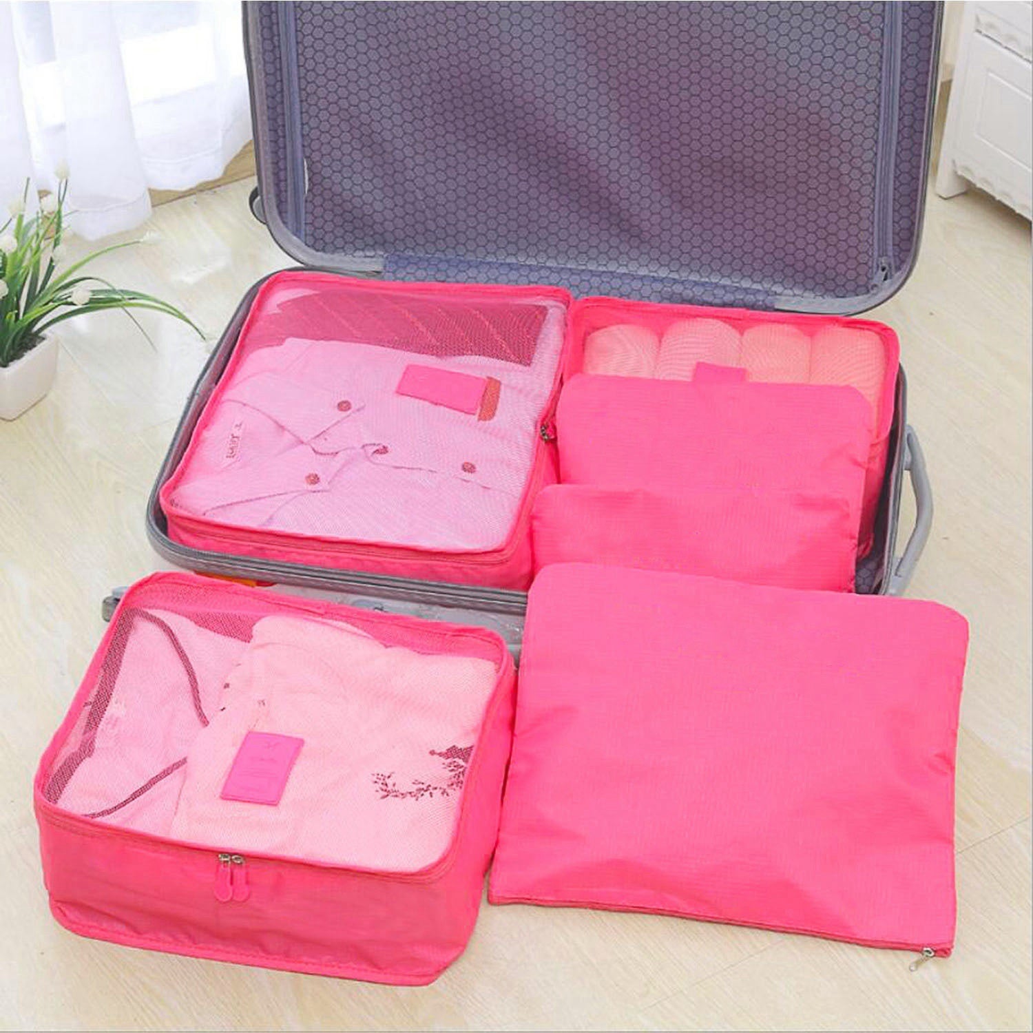 Set of four 9Pcs Clothes Storage Bags Water-Resistant Travel Luggage Organizer Clothing Packing Cubes of varying sizes with clothing items, displayed next to a folded floral blouse, all on a white background.