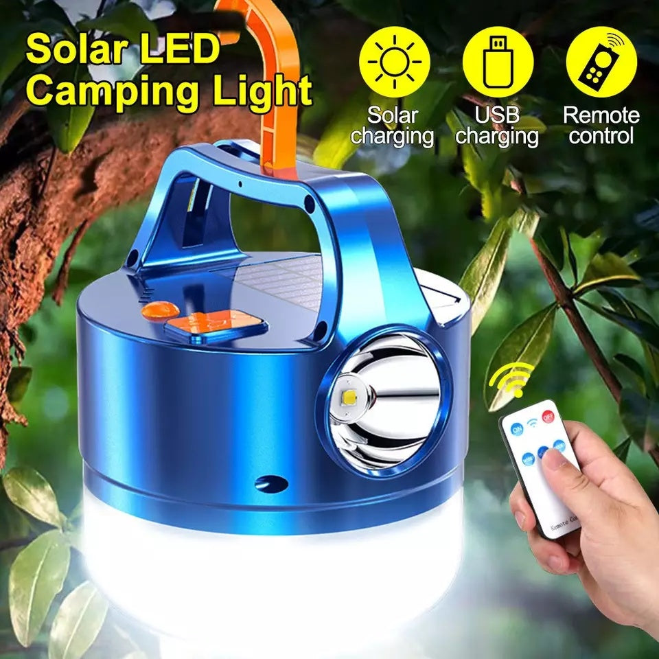A blue 3N1 Solar Lantern With Remote hanging from a tree branch in a forest setting, ideal for outdoor adventures.