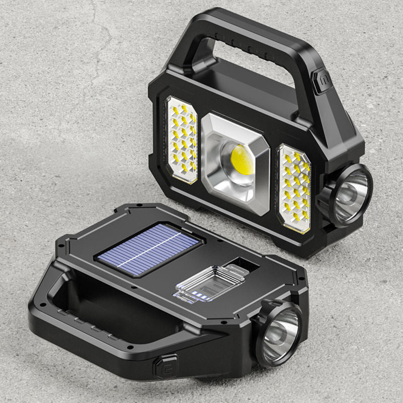 A hand holding a 2N1 Solar COB Work Light featuring a central spotlight and two side lights.