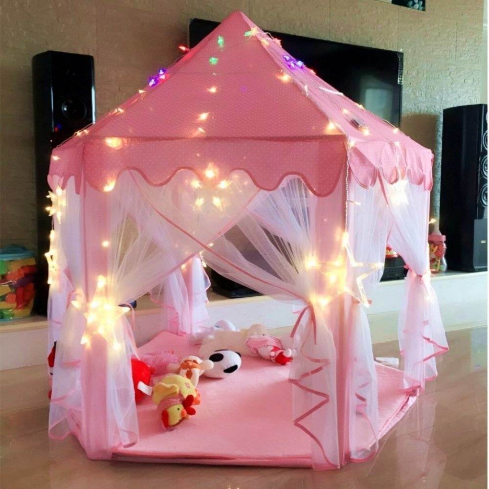 A purple children's Outdoor Indoor Portable Folding Princess Castle Tent Kids Children Funny Play Fairy House Kids Play Tent(LED Star Lights) illuminated by fairy lights at night, set up outdoors near a building.