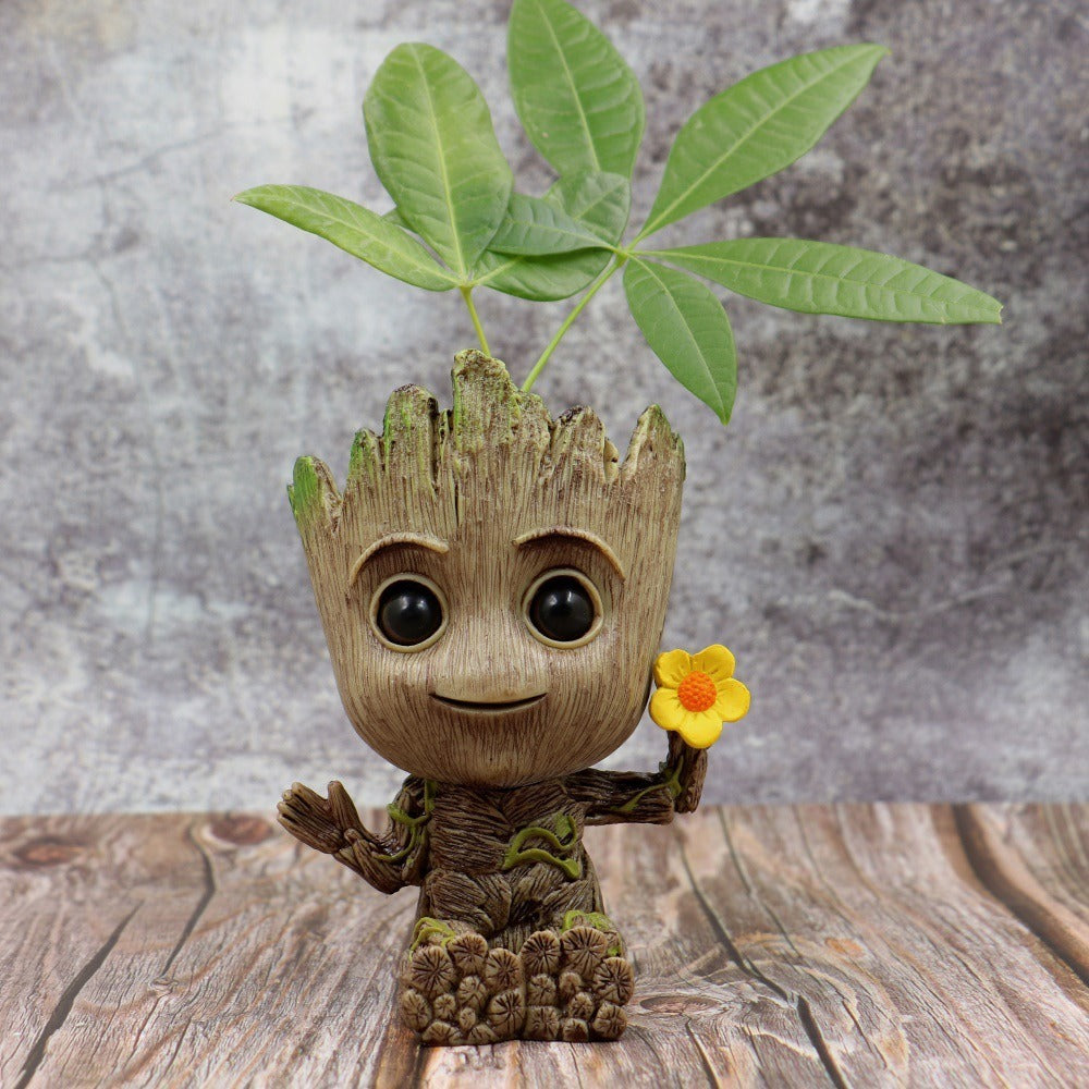 A Guardians of the Galaxy Groot Tree Man Hand Ornament, crafted from PVC, holding a small bird, with green leaves sprouting from its head, isolated on a white background.