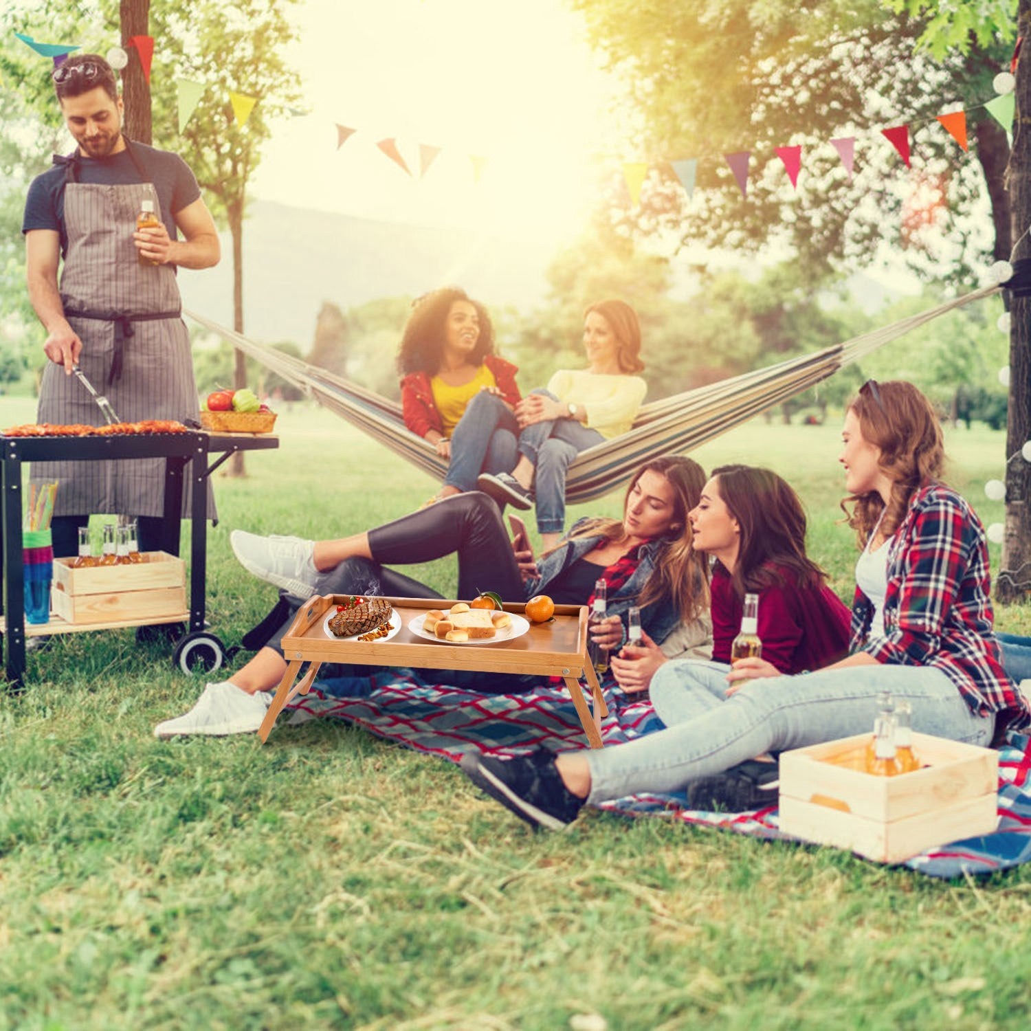 Bamboo Folding Bed Table Breakfast Tray with legs, holding a cup, fruits, a jar of nuts, and a plate with cheese and crackers, on a white background.