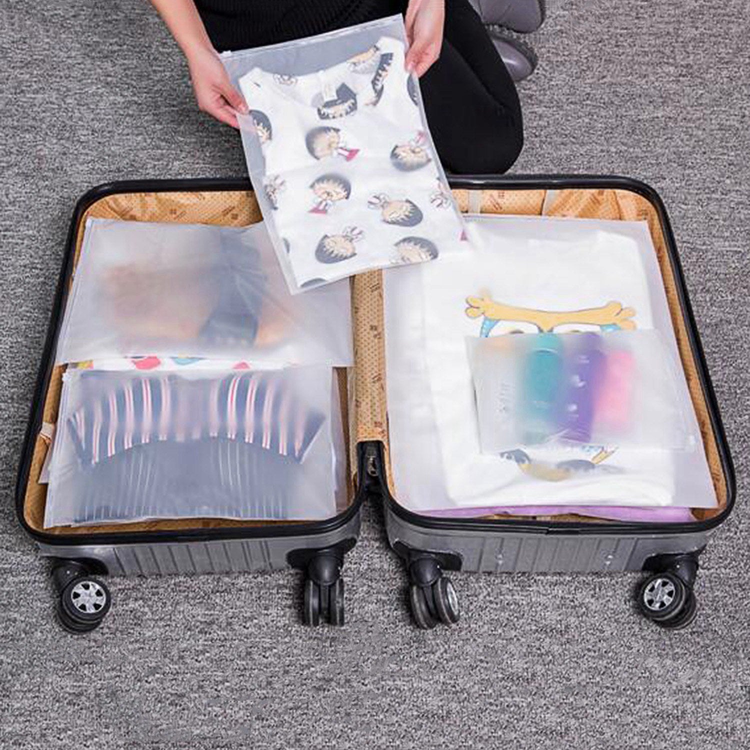 Set of four 9Pcs Clothes Storage Bags Water-Resistant Travel Luggage Organizer Clothing Packing Cubes of varying sizes with clothing items, displayed next to a folded floral blouse, all on a white background.