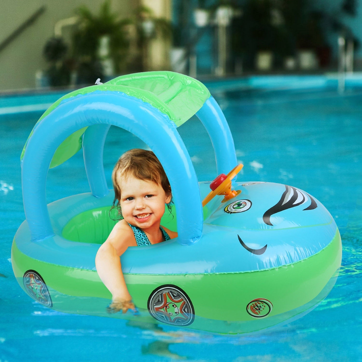 A young child smiles while sitting in a colorful Baby Inflatable Pool Float Car Shaped Toddler Swimming Float Boat Pool Toy Infant Swim Ring Pool with Sun Protection Canopy for 1-3 Year-Old Kids Infant Toddlers in a swimming pool.