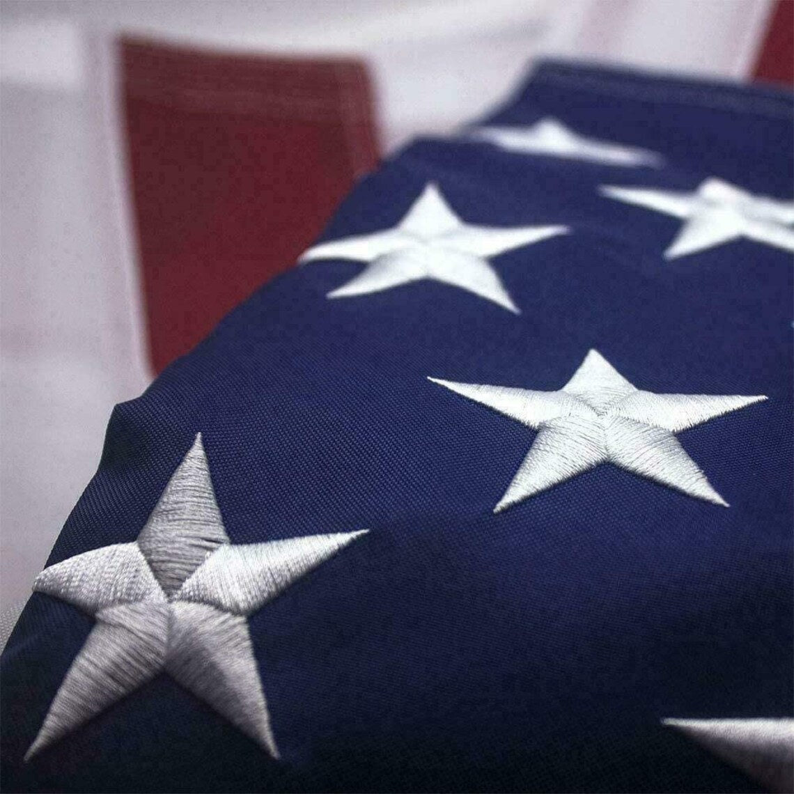 An American Flag 5x8 ft with a unique design, featuring a single large star replacing the usual field of 50 stars, against the standard thirteen red and white stripes. The star is intricately embroidered, showcasing detailed craftsmanship.