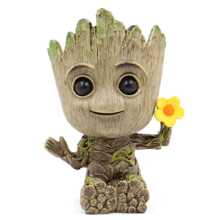 A Guardians of the Galaxy Groot Tree Man Hand Ornament, crafted from PVC, holding a small bird, with green leaves sprouting from its head, isolated on a white background.