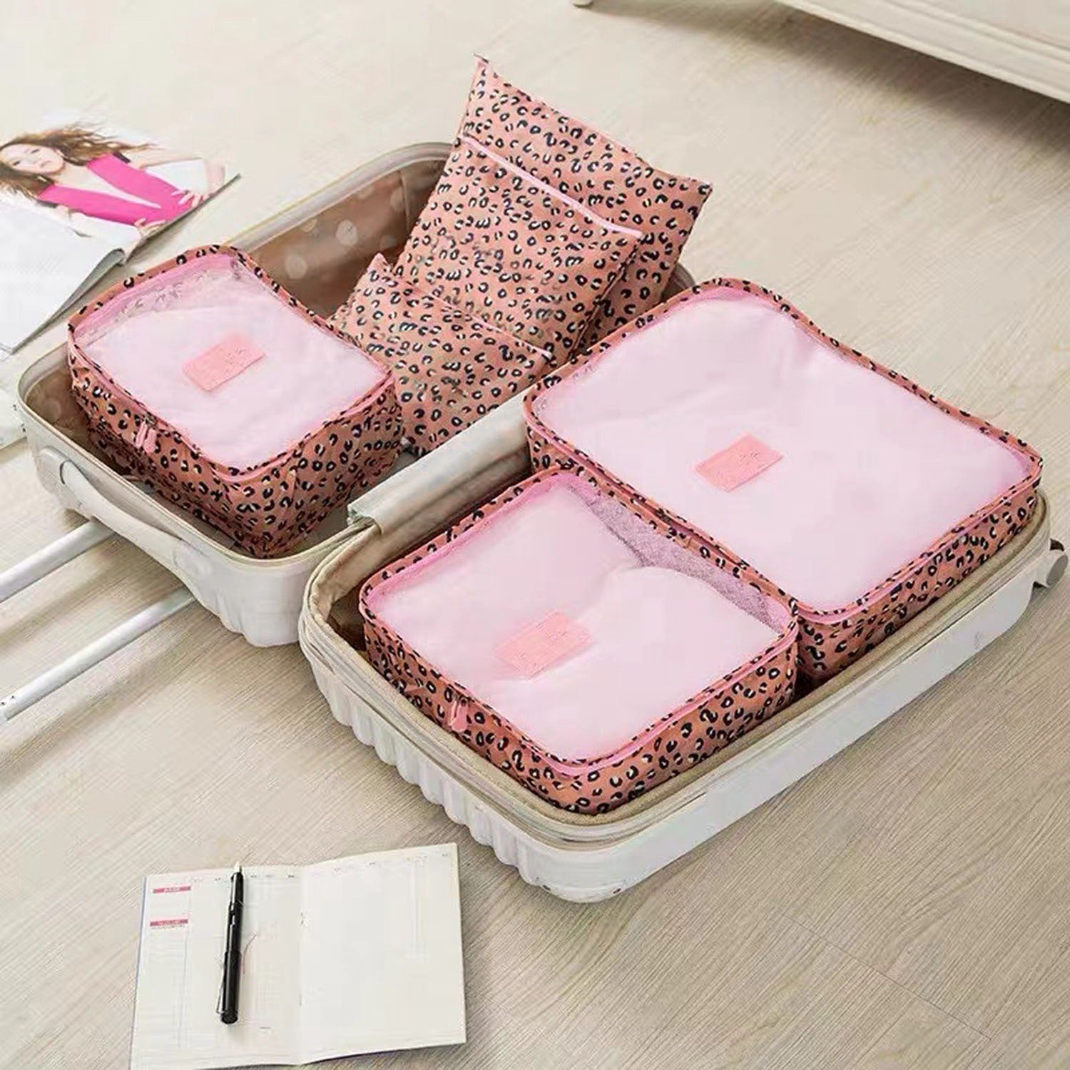 Set of four 9Pcs Clothes Storage Bags Water-Resistant Travel Luggage Organizer Clothing Packing Cubes of varying sizes with clothing items, displayed next to a folded floral blouse, all on a white background.