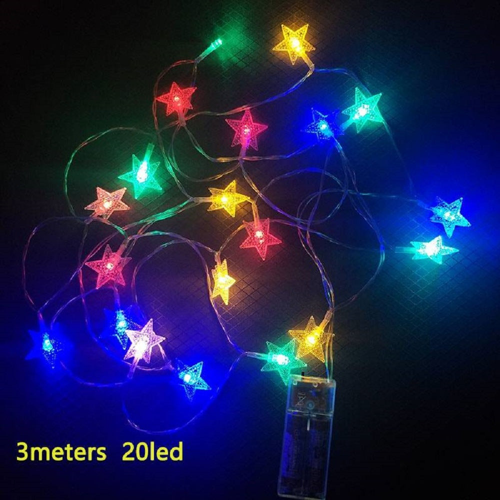 A purple children's Outdoor Indoor Portable Folding Princess Castle Tent Kids Children Funny Play Fairy House Kids Play Tent(LED Star Lights) illuminated by fairy lights at night, set up outdoors near a building.