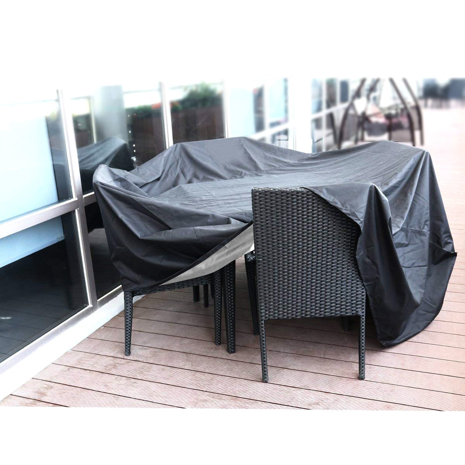 Large black 210D Waterproof Outdoor Furniture Cover made of Oxford cloth on a balcony, labeled as waterproof, anti-UV, windproof, and snow resistant, with an inset showing the cover in use and its storage bag.